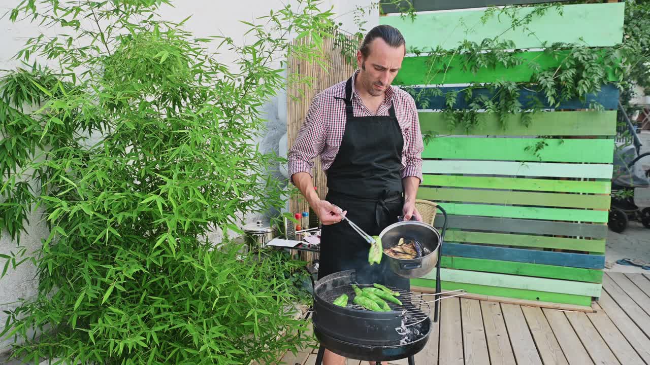 后院烧烤与男子烤蔬菜在一个夏天的一天，周围是郁郁葱葱的绿色植物和一个轻松的户外氛围。视频素材