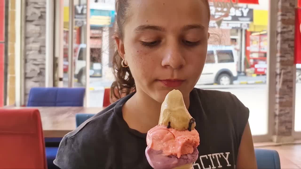 可爱的女孩在冰淇淋店里愉快地舔着他的冰淇淋视频下载