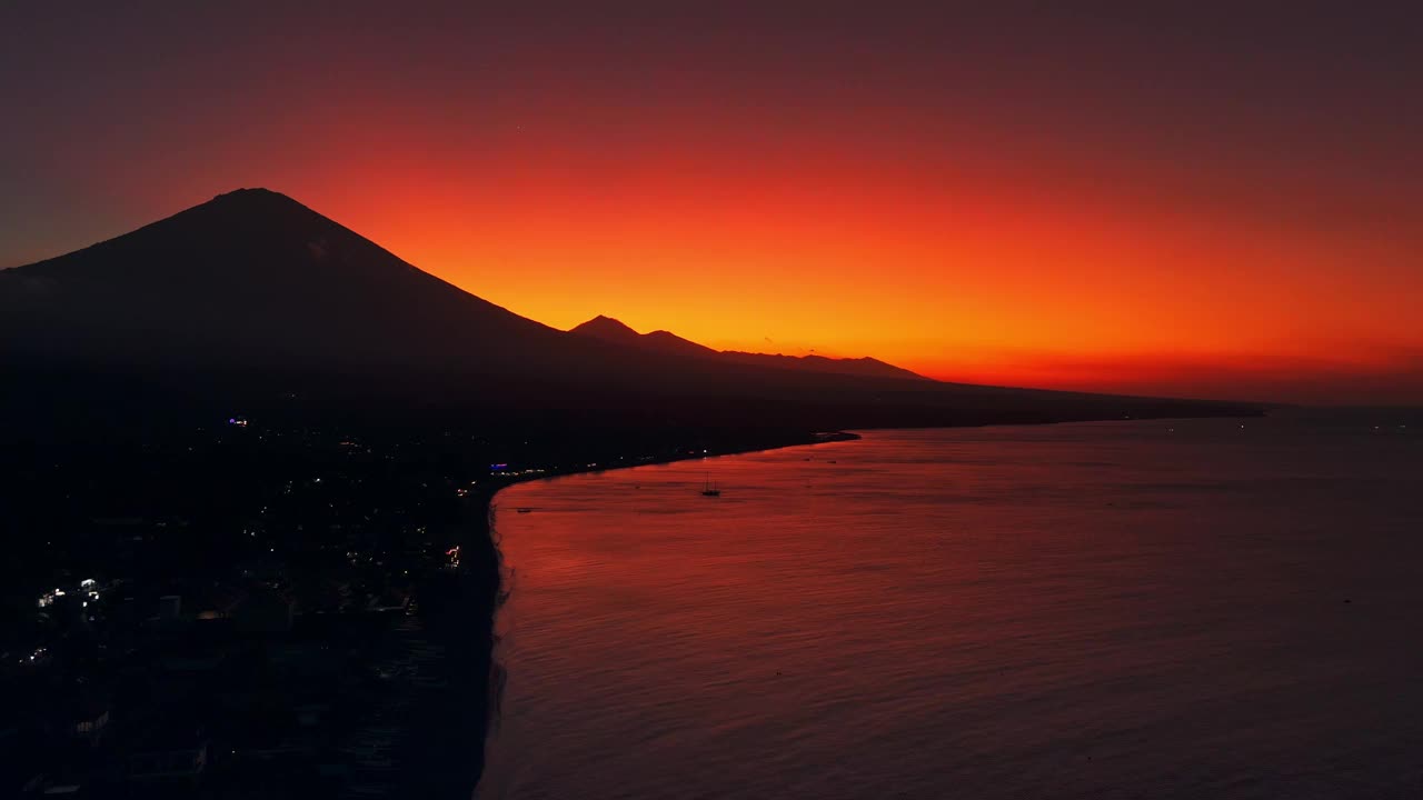 海岸线的剪影与火山山在明亮的日落。巴厘岛的无人机景观视频下载