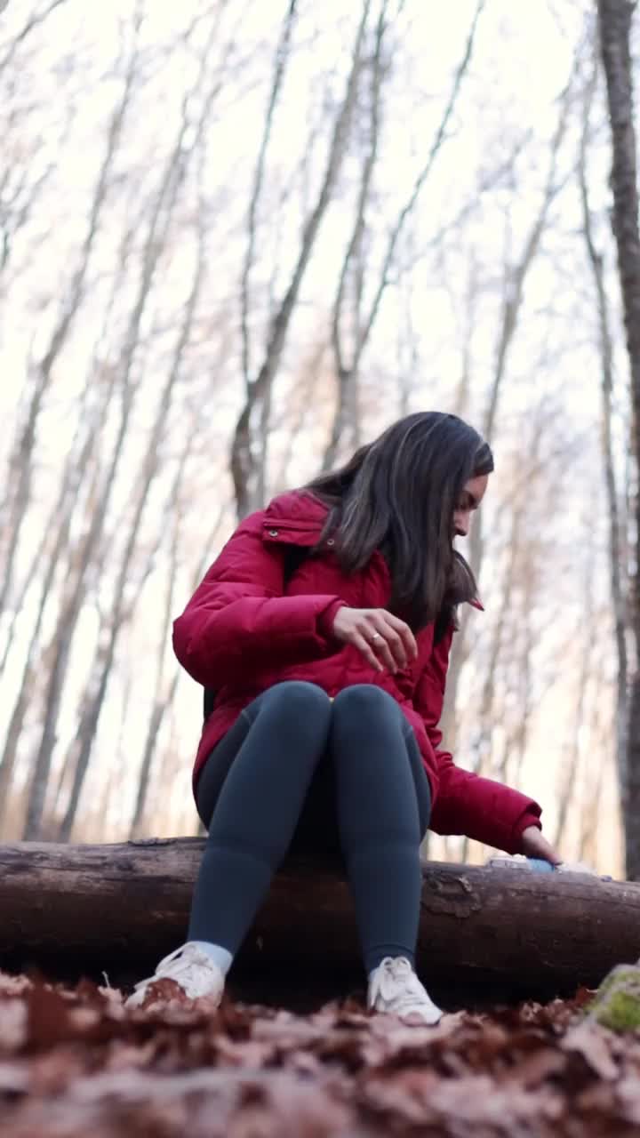 冬天徒步旅行后坐在森林里喝水的拉丁妇女。视频下载