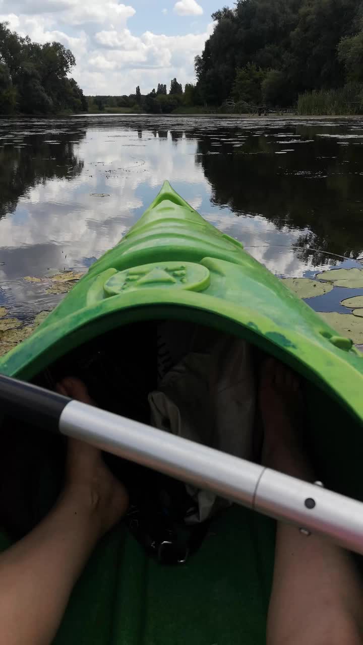 一艘皮艇的船首在镜面上平稳地滑行，倒影出多云的蓝天视频下载