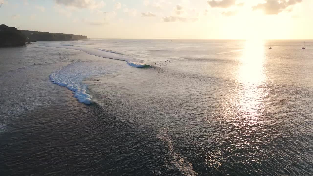 在海浪上冲浪，伴着夕阳的色调。与冲浪者在巴厘岛的完美海浪视频下载