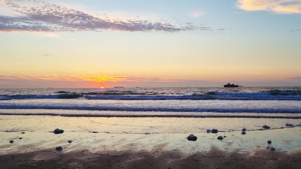 宁静的海滩日落与平静的海浪和遥远的船视频下载