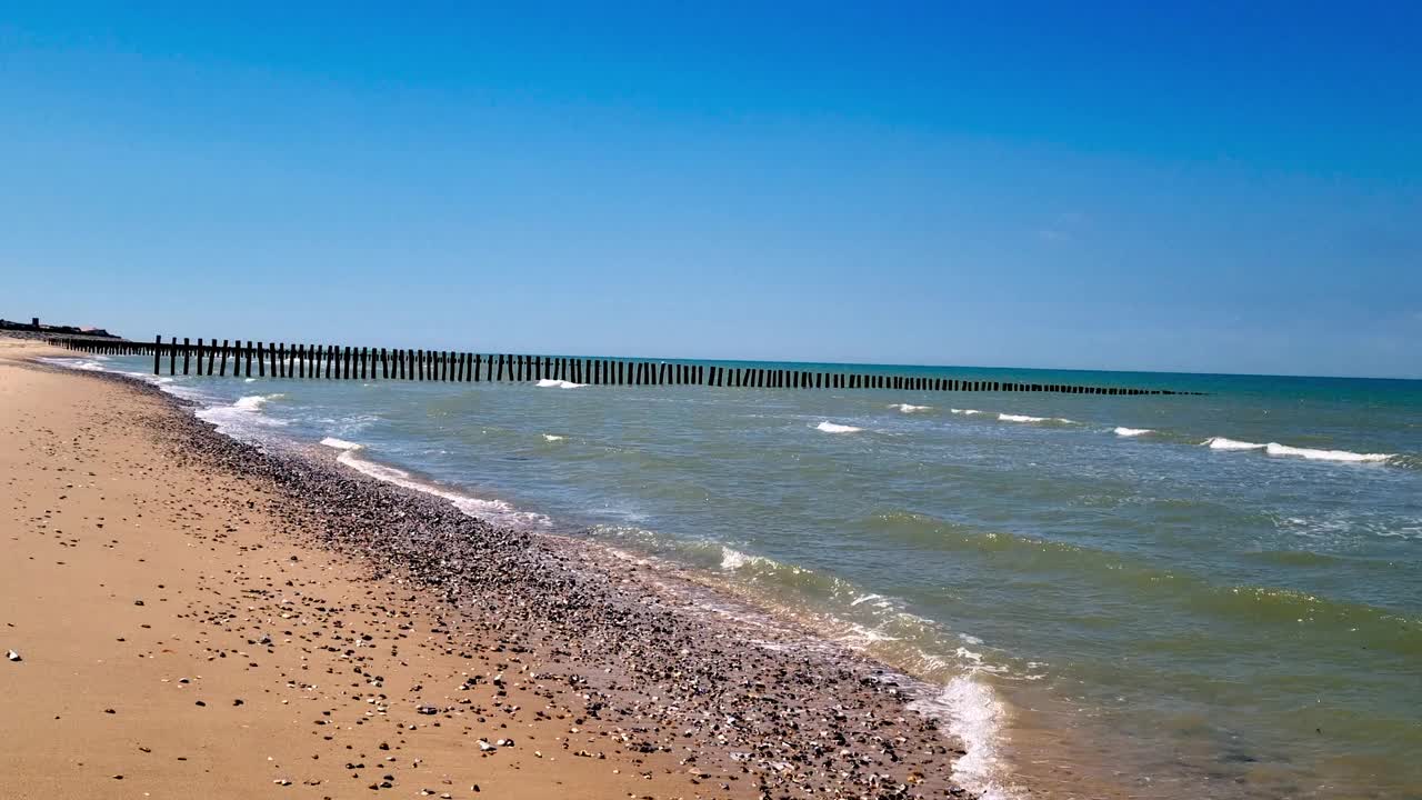 宁静的夏日海滩，木制码头和海岸线上的温柔海浪视频下载