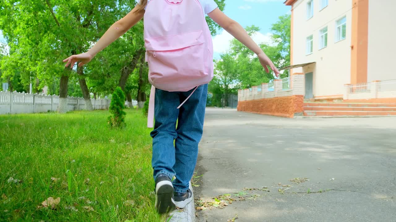 快乐的小女孩回到学校。孩子背着书包上学。背着背包的女孩走过校园。幸福家庭概念。回到学校。在学校操场上，一个女孩背着粉红色的背包去上学视频素材