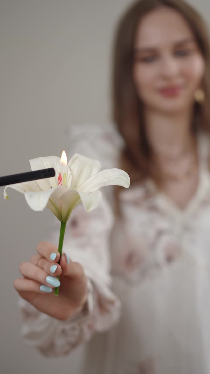 一位年轻女子手持一朵美丽的燃烧的白花，捕捉艺术表达和情感视频素材