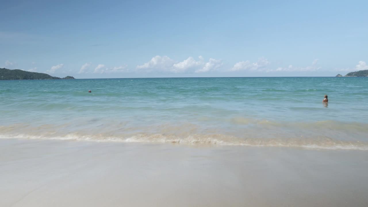 在阳光明媚的下午，海浪拍打着白色的沙滩，海滩表面的自然景观视频下载