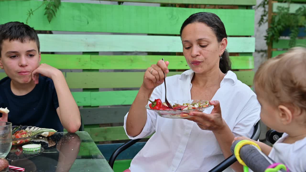 在阳光明媚的日子里，一家人享受着舒适的户外大餐和新鲜的蔬菜视频素材