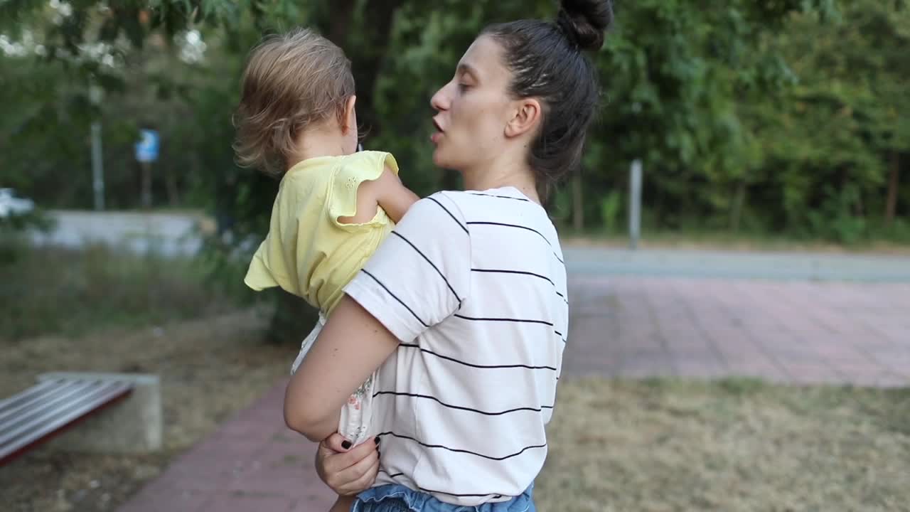 年轻的母亲抱着她蹒跚学步的女儿视频下载