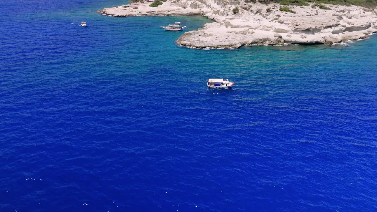 游船在碧绿的海水中沿着多石的海岸线航行。他们在海岸附近航行，为游客提供风景视频素材