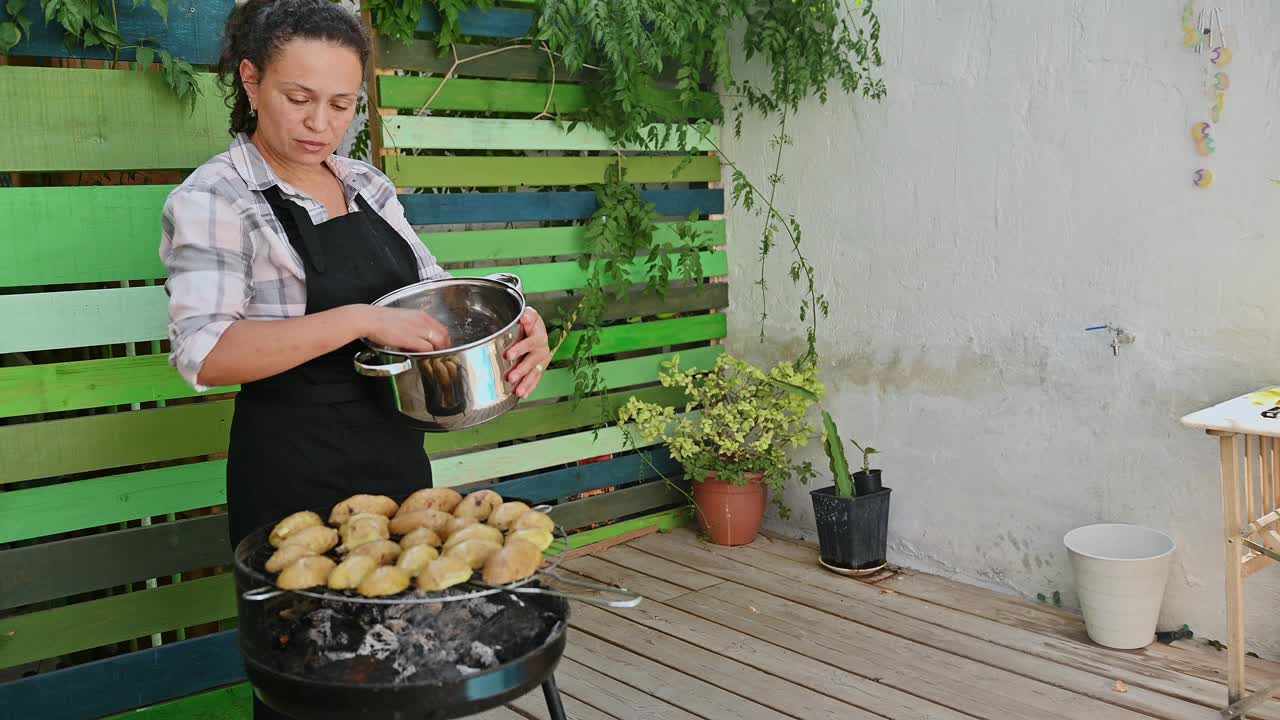 妇女准备海鲜烧烤在户外花园设置与新鲜香草和乡村的氛围。在自然、轻松的环境中享受夏日烹饪和烧烤。视频素材