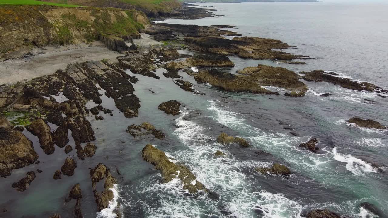 在图像的左上方有一个小海滩，其余部分是岩石海岸地区，周围是大海。视频下载