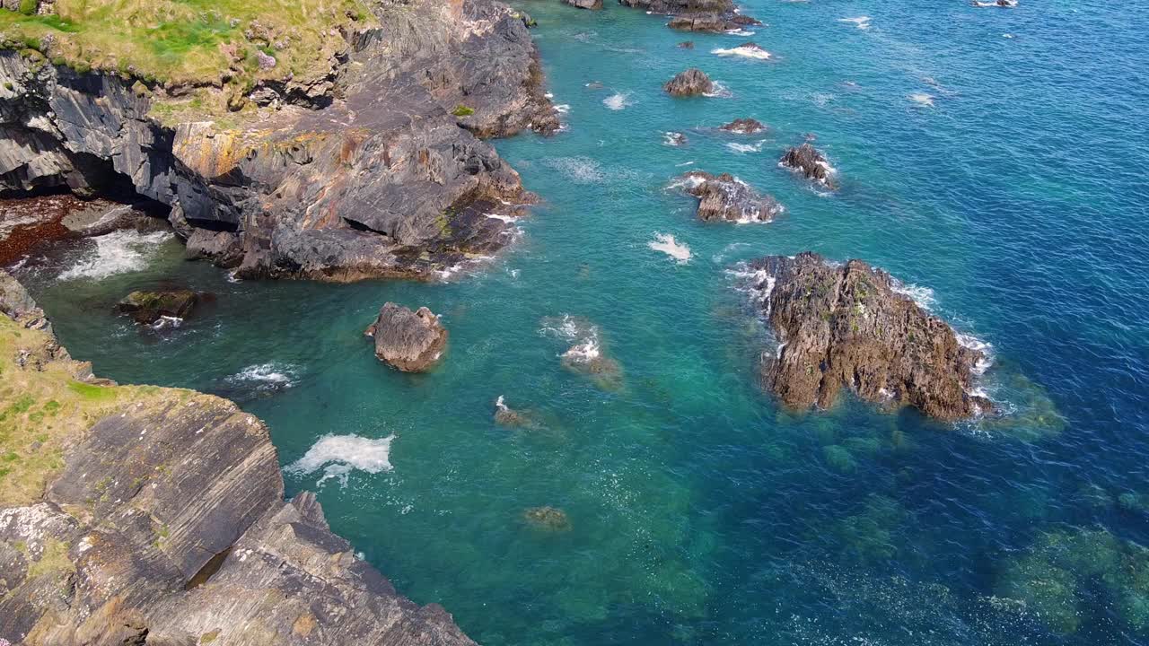 海洋是浅蓝色和深蓝色的混合，海浪拍打着岩石和海岸线。视频下载