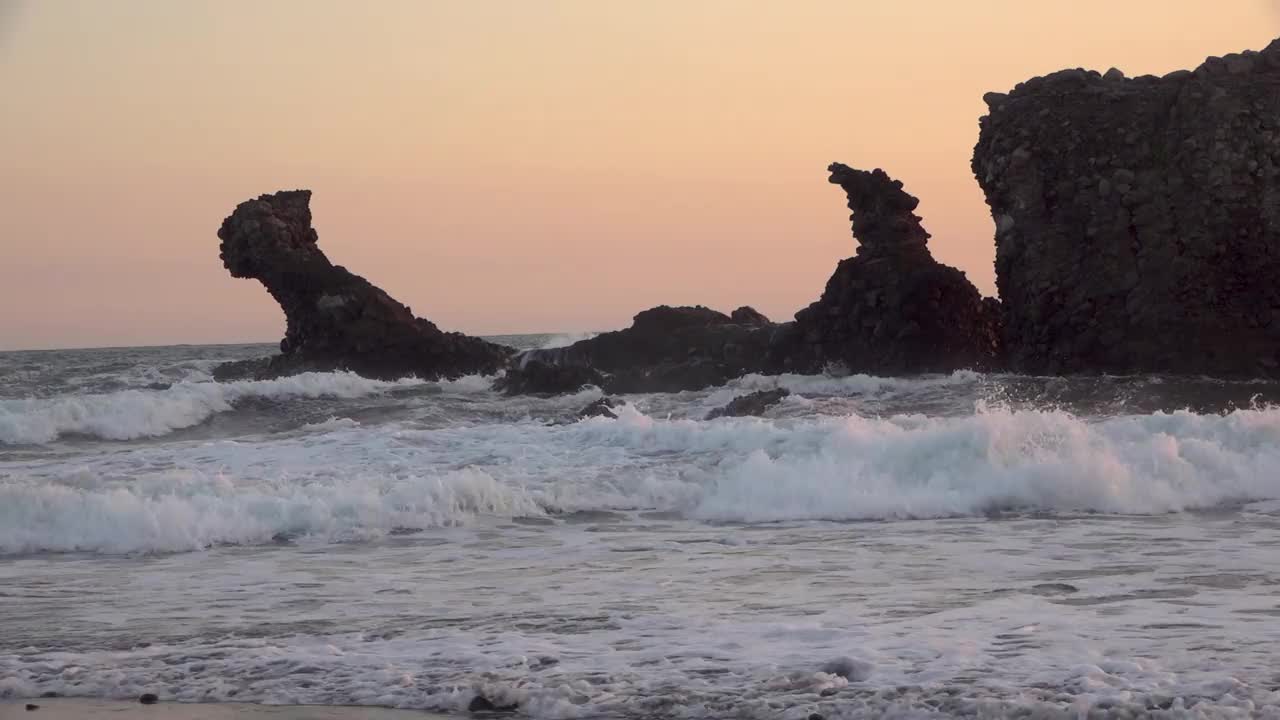 缓慢的海浪冲击着海岸线上的一块大岩石视频素材