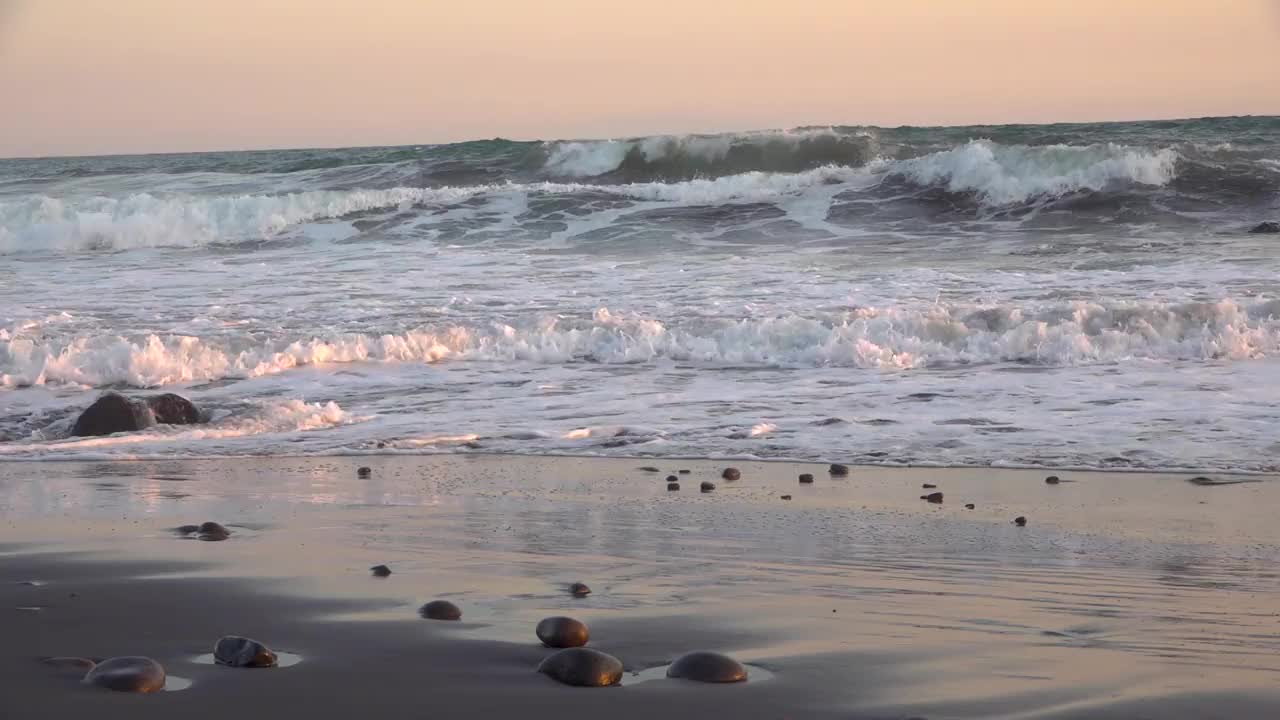 日落时，海浪拍打着海滩视频素材