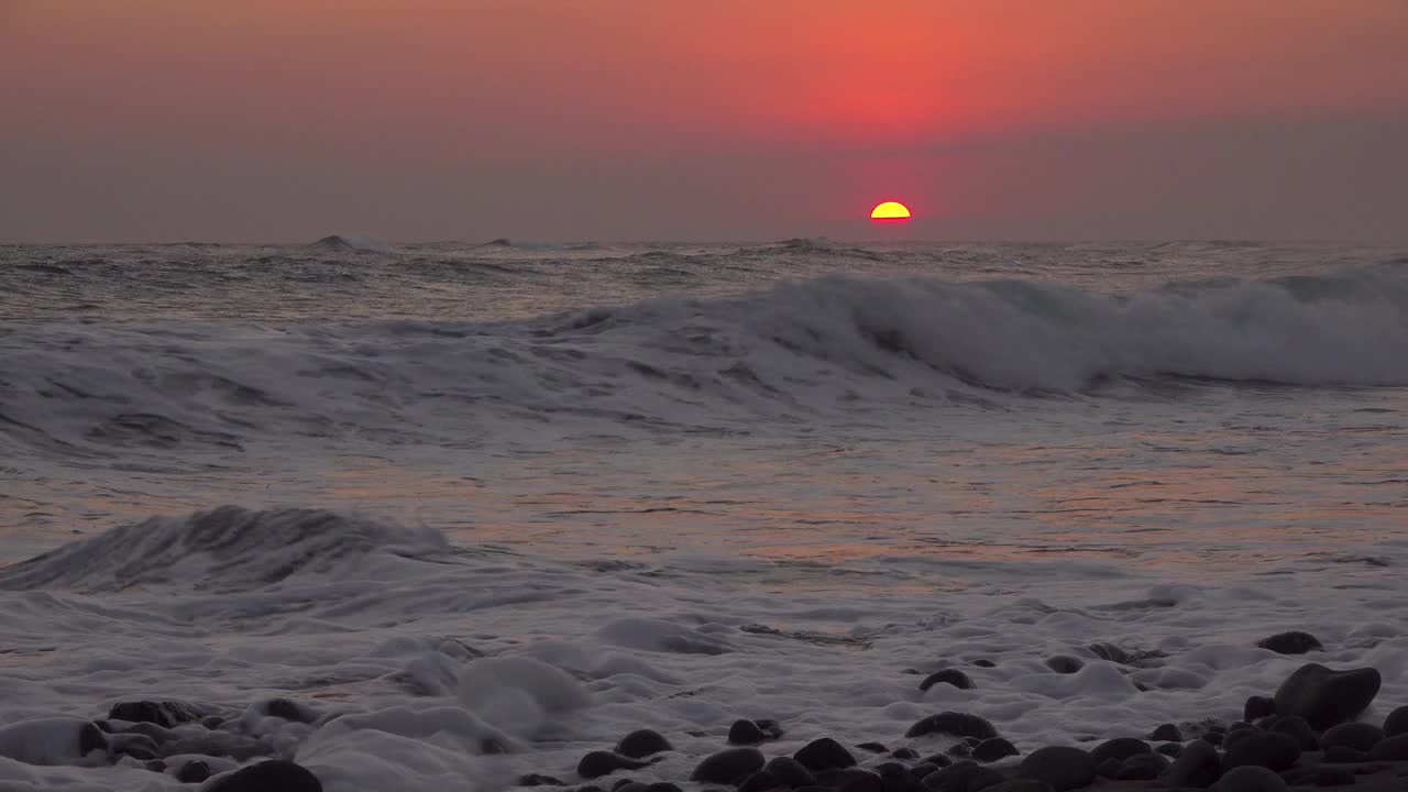 当红色的太阳落在他们身后时，冲浪者在海洋上视频下载