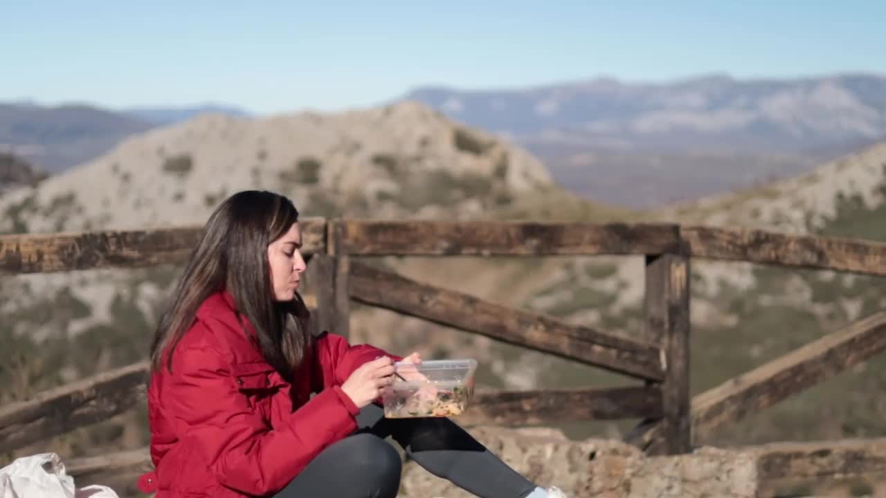 拉丁妇女在大自然中徒步旅行时休息和吃一些食物。视频下载