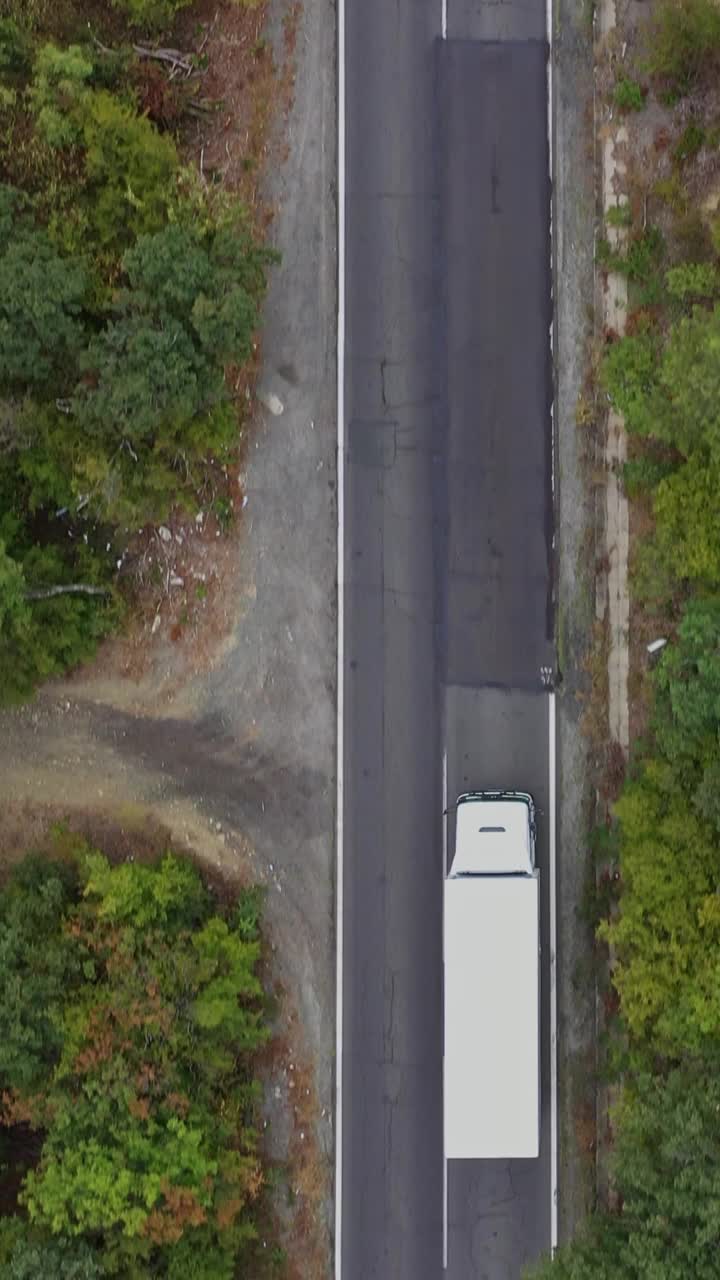 从空中俯瞰的白色卡车行驶在道路上的森林视频下载