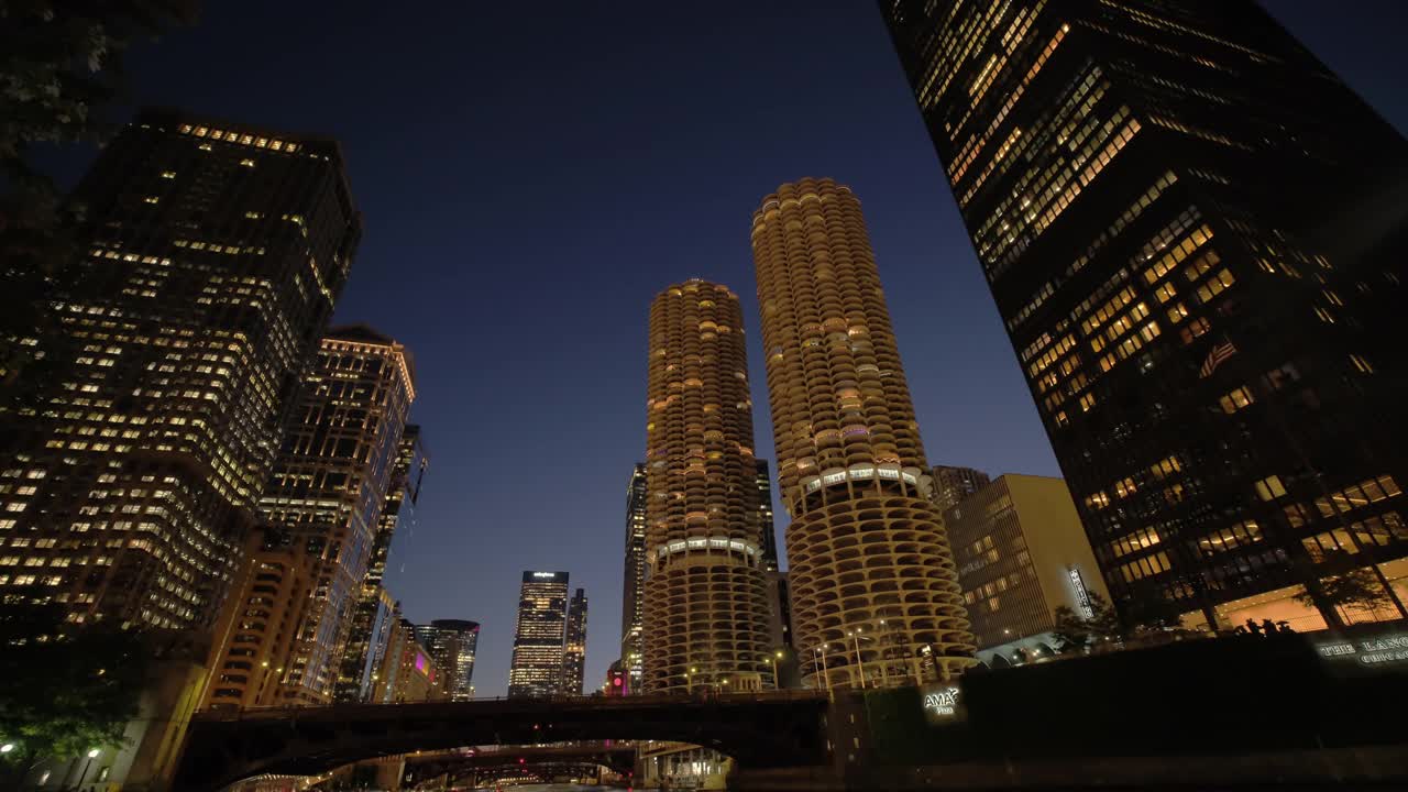 傍晚芝加哥市中心滨河步行街的全景。充满活力的建筑和城市灯光在河上闪烁的倒影视频下载