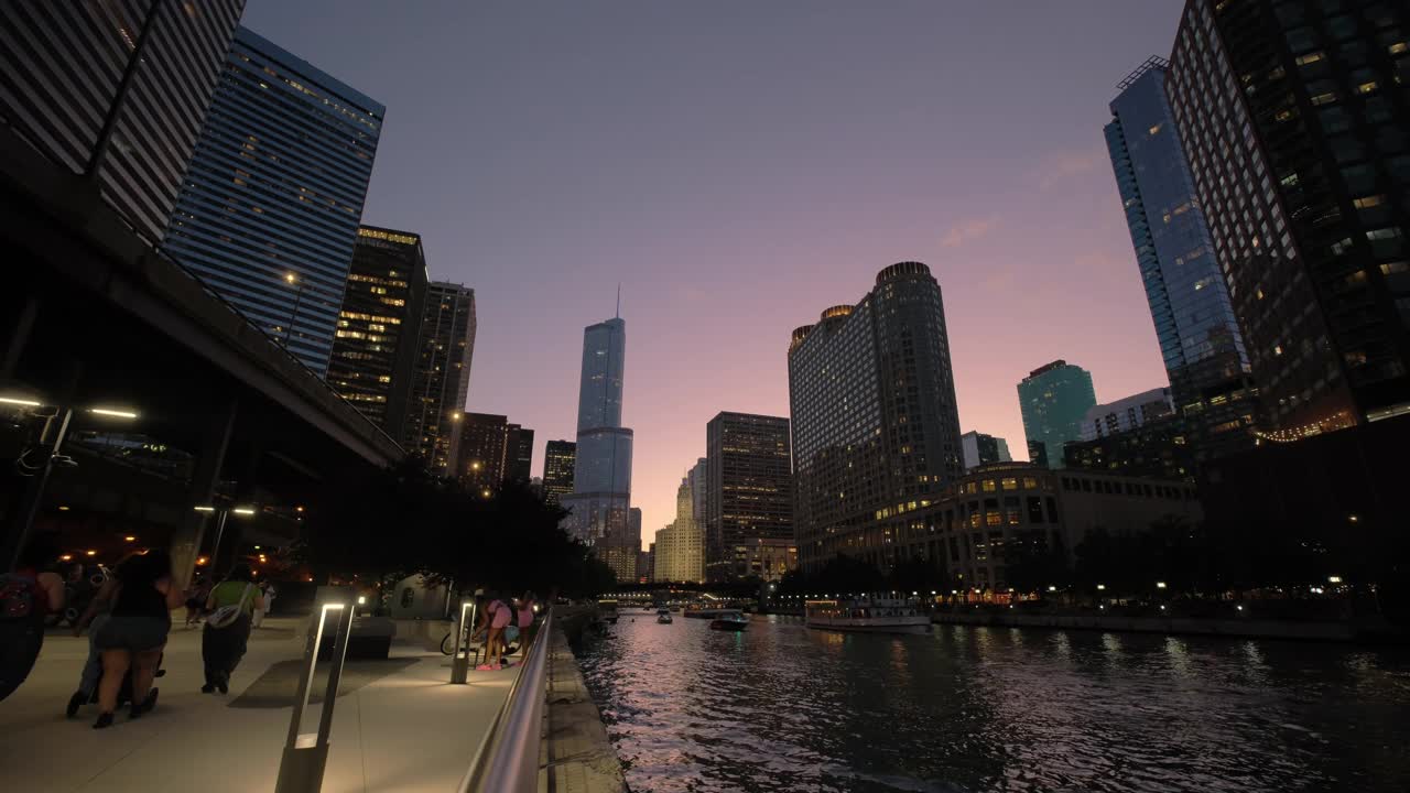 芝加哥市中心滨河步行街的夜间全景镜头。充满活力的建筑和城市灯光在河上闪烁的倒影视频下载