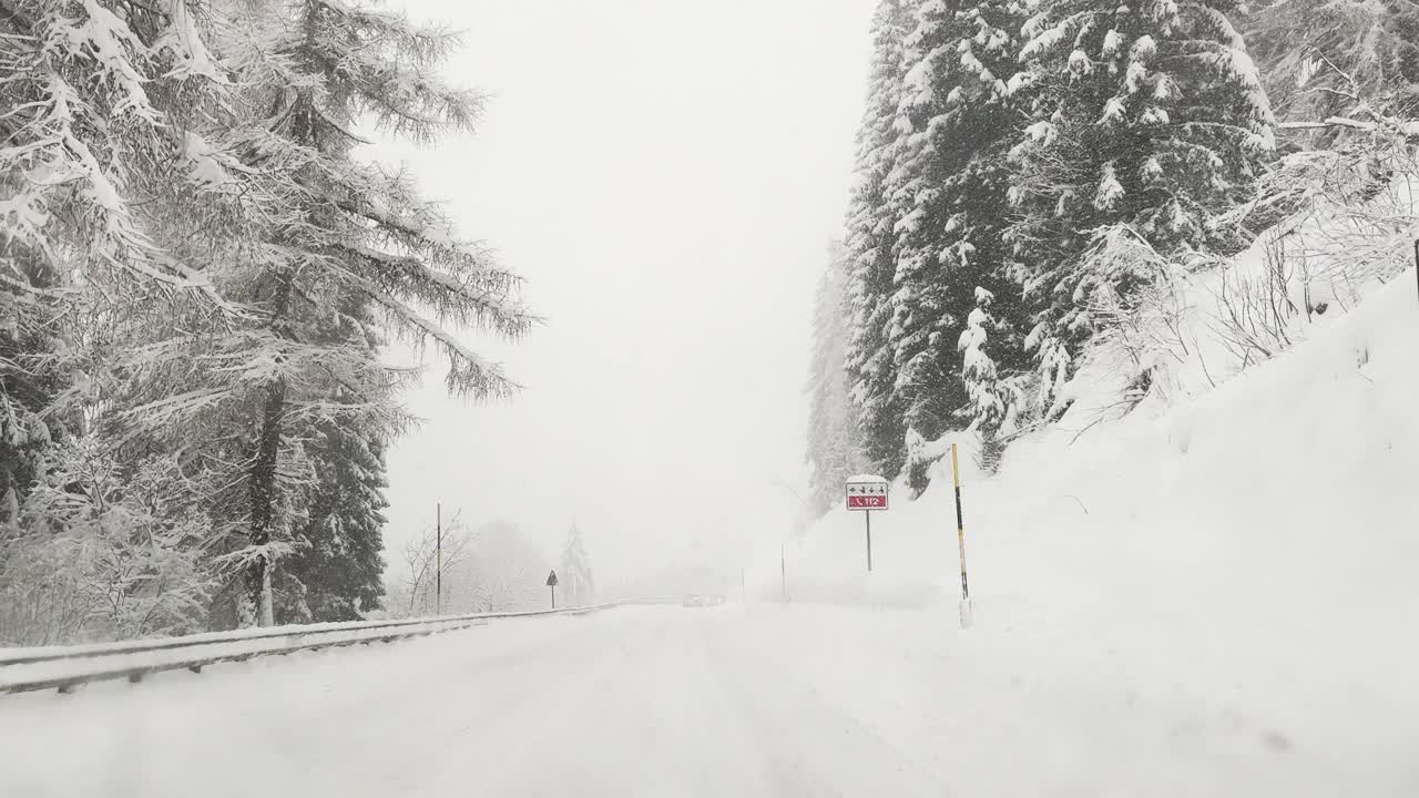 在暴风雪中行驶在覆盖着厚厚的积雪的山路上视频下载