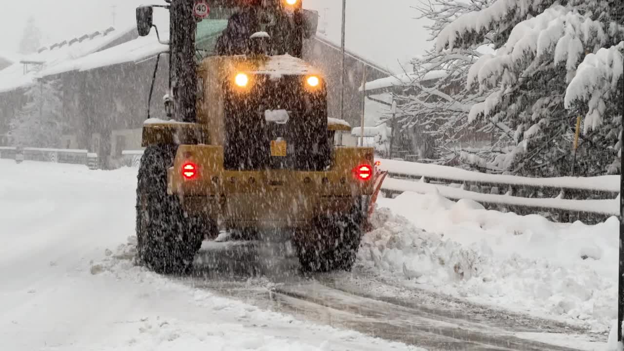 暴风雪中，推土机铲开被雪覆盖的街道视频下载