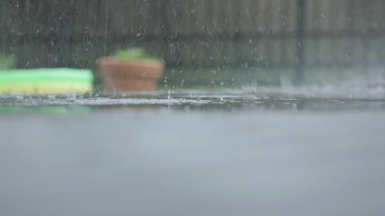 夏季白天暴雨天气，大雨落在水坑雨滴飞溅视频下载