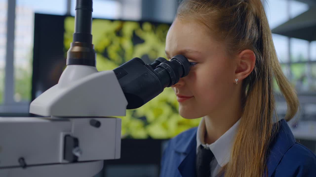 小女孩在生物或化学课上透过显微镜观察的肖像视频下载