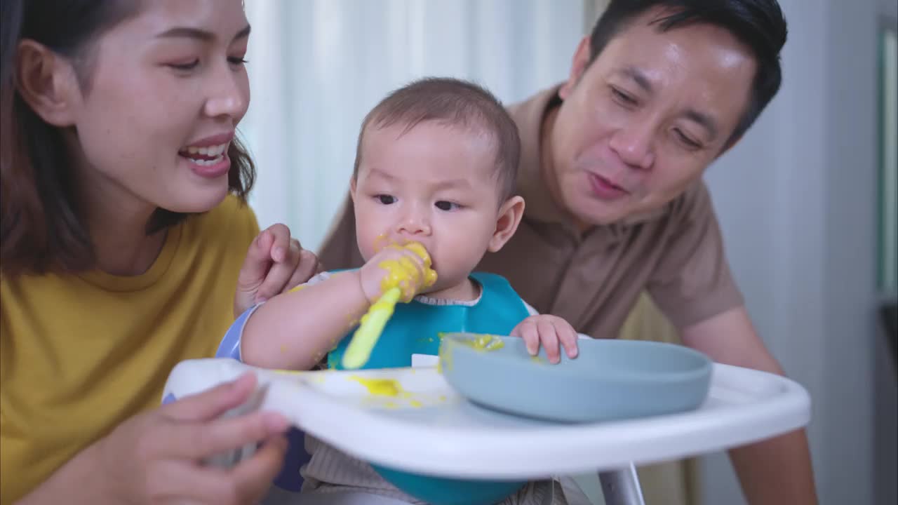 一个小孩子吃了他的第一顿饭，父母兴奋地欢呼视频素材