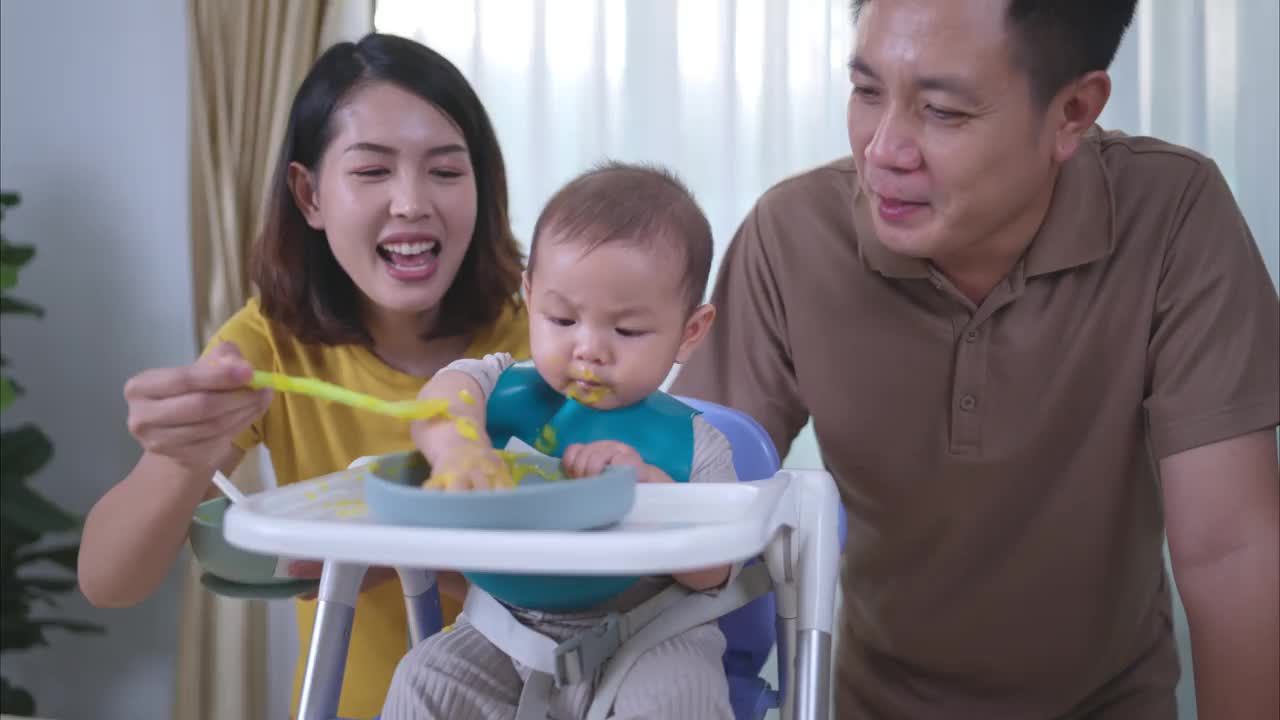 一个小孩子吃了他的第一顿饭，父母兴奋地欢呼视频素材