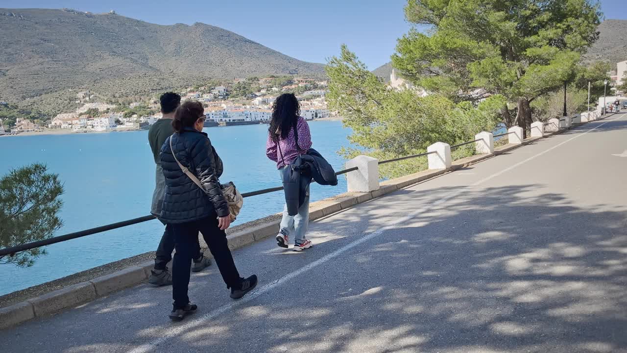 一群人沿着卡达夸斯湾的海岸散步，宁静的景色，西班牙加泰罗尼亚视频下载