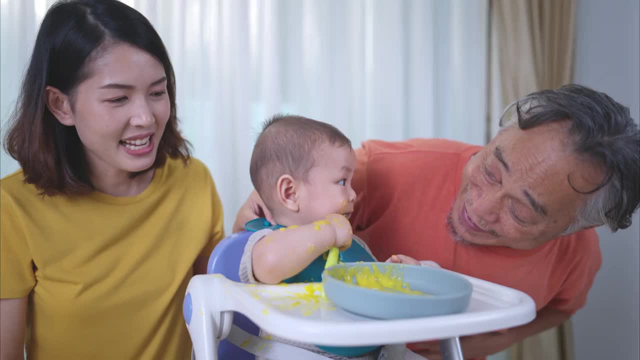 一个小孩吃了他的第一顿饭，妈妈和爷爷兴奋地欢呼视频下载