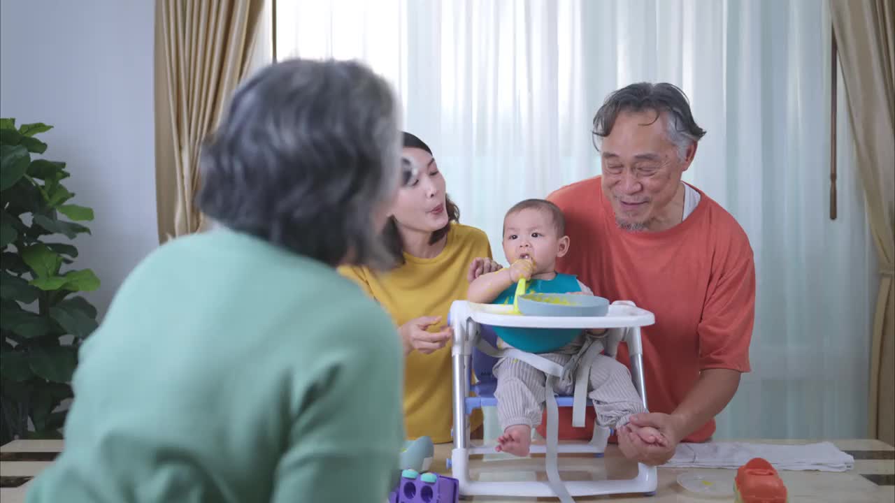 一个小孩吃了他的第一顿饭，父母和祖父母兴奋地欢呼视频下载