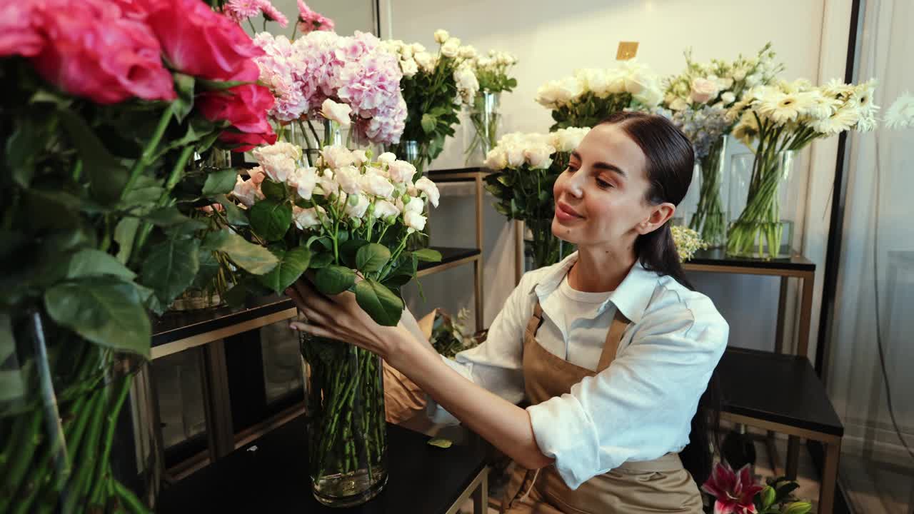 女花匠在花店里整理一束白玫瑰视频素材