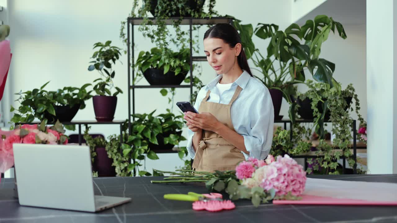 微笑的花店老板在她的花店使用智能手机视频素材