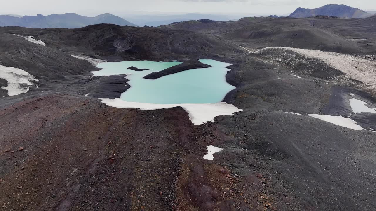 高山死气沉沉的湖泊，冰川和火山灰正在融化。冰岛荒凉的绿松石湖景观在一个阴天视频下载