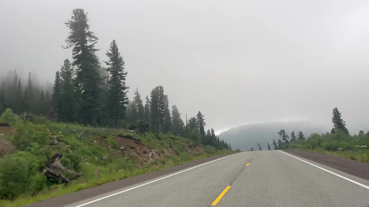 从雾蒙蒙的山路上的车窗观看。汽车沿着风景行驶。旅行，旅行，开车旅行。运输的概念视频下载