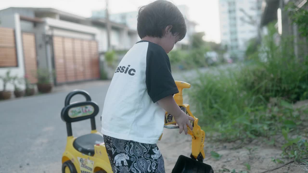 小男孩想象着开着推土机，一边玩一边练习用手臂肌肉铲沙子。视频素材