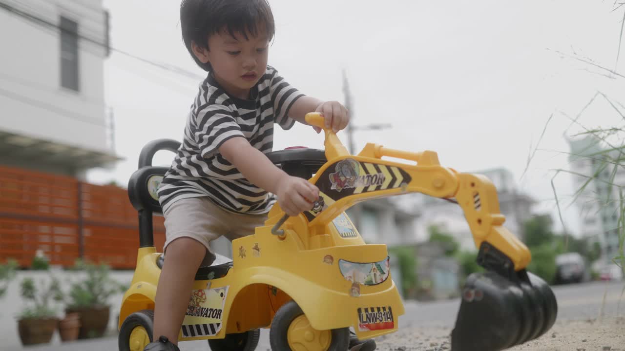 小男孩想象着开着推土机，一边玩一边练习用手臂肌肉铲沙子。视频素材