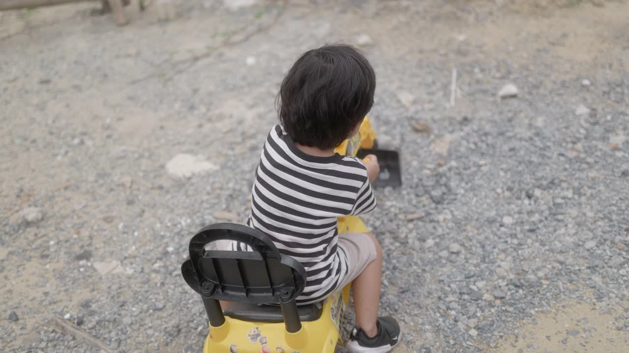 小男孩想象着开着推土机，一边玩一边练习用手臂肌肉铲沙子。视频素材