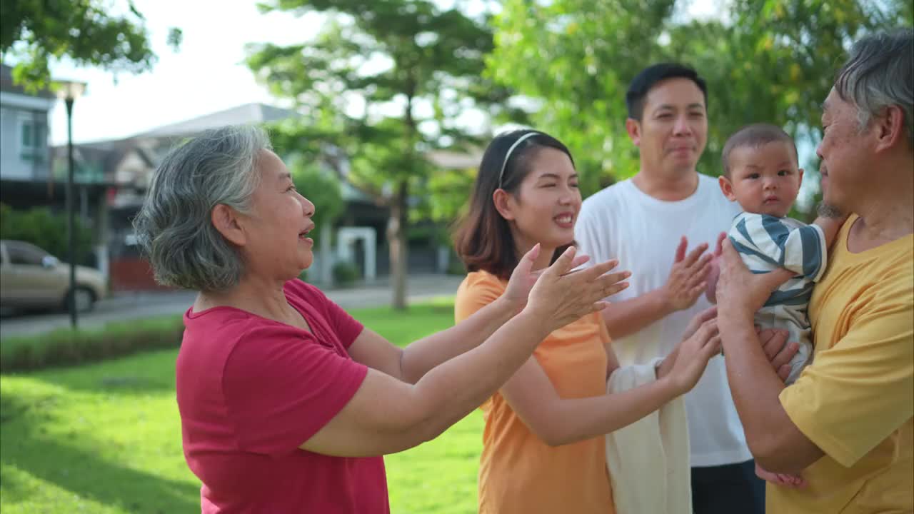 爷爷奶奶和带着小孩的父母正在公园里玩耍和休息视频素材