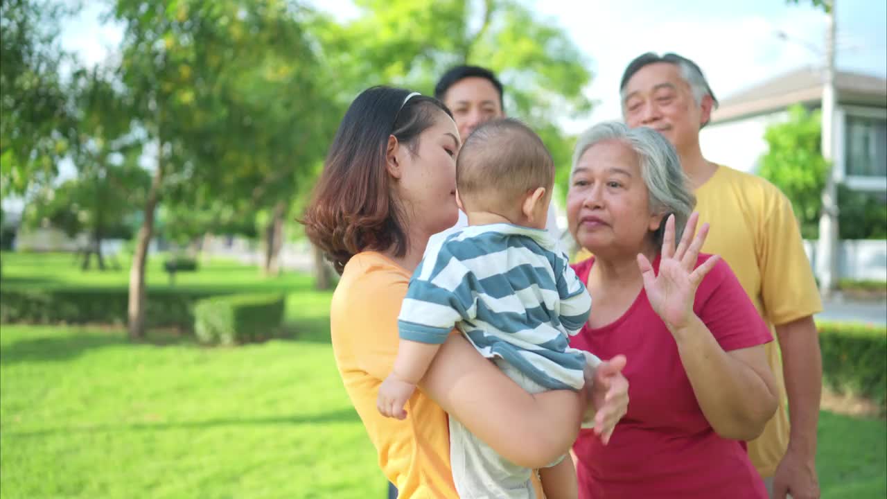 爷爷奶奶和带着小孩的父母正在公园里玩耍和休息视频下载