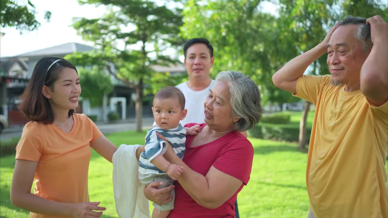 爷爷奶奶和带着小孩的父母正在公园里玩耍和休息视频素材