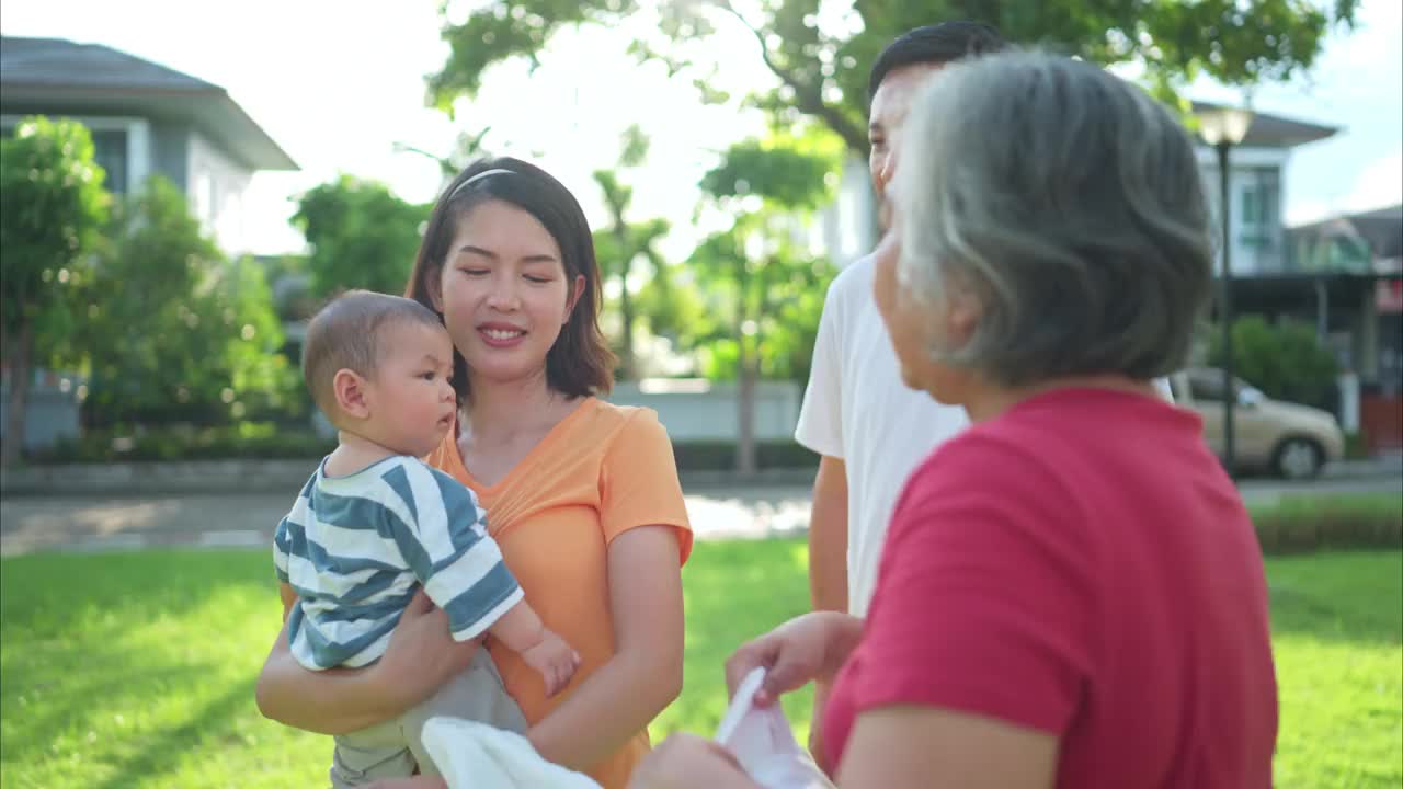 爷爷奶奶和带着小孩的父母正在公园里玩耍和休息视频素材