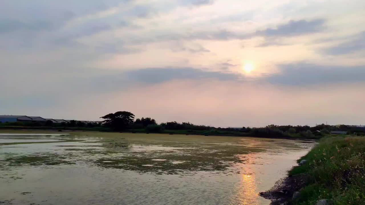 宁静的池塘上平静的日落，柔和的光线穿透云层视频素材