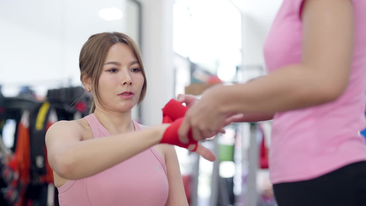 一个穿粉红色衬衫的女人正在帮另一个女人拿拳击手套视频下载