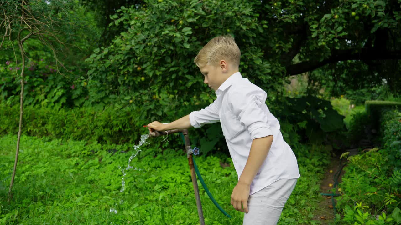 孩子们在夏天的花园里玩水。女孩和男孩滑稽地抓水。视频素材