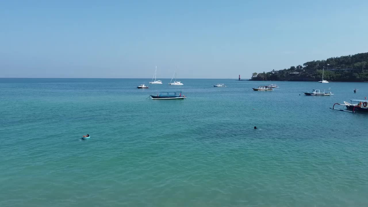 夏天的风景。鸟瞰在印尼圣吉吉海滩绿松石海中的船只群视频下载