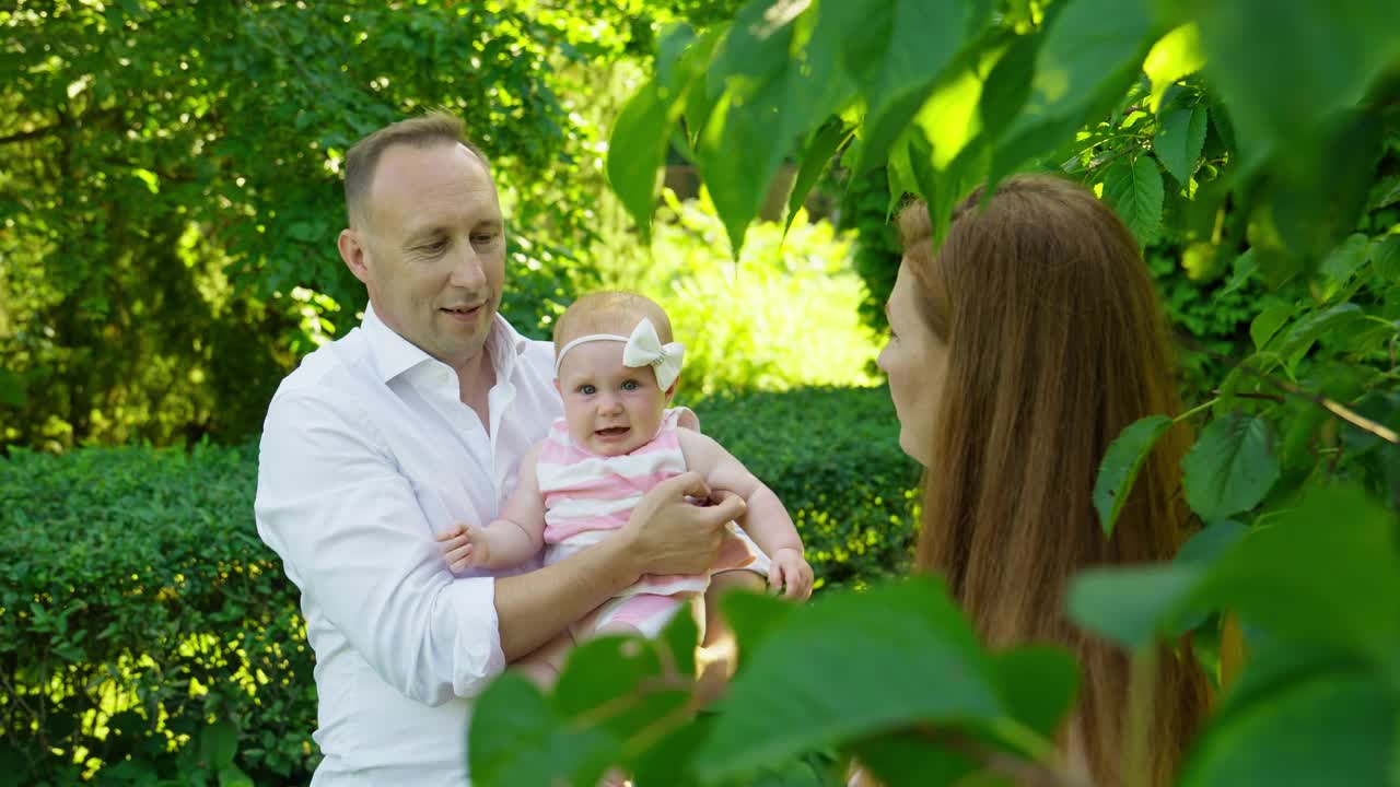 夏日花园中的年轻家庭。幸福的一家人一起在户外玩耍。视频素材