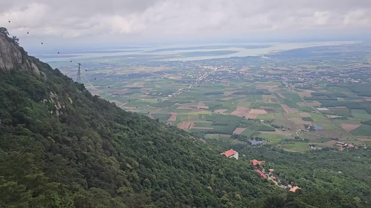 缆车沿着山坡在巴登山，Tay Ninh，越南。稻田和蓝天白云的背景。视频下载